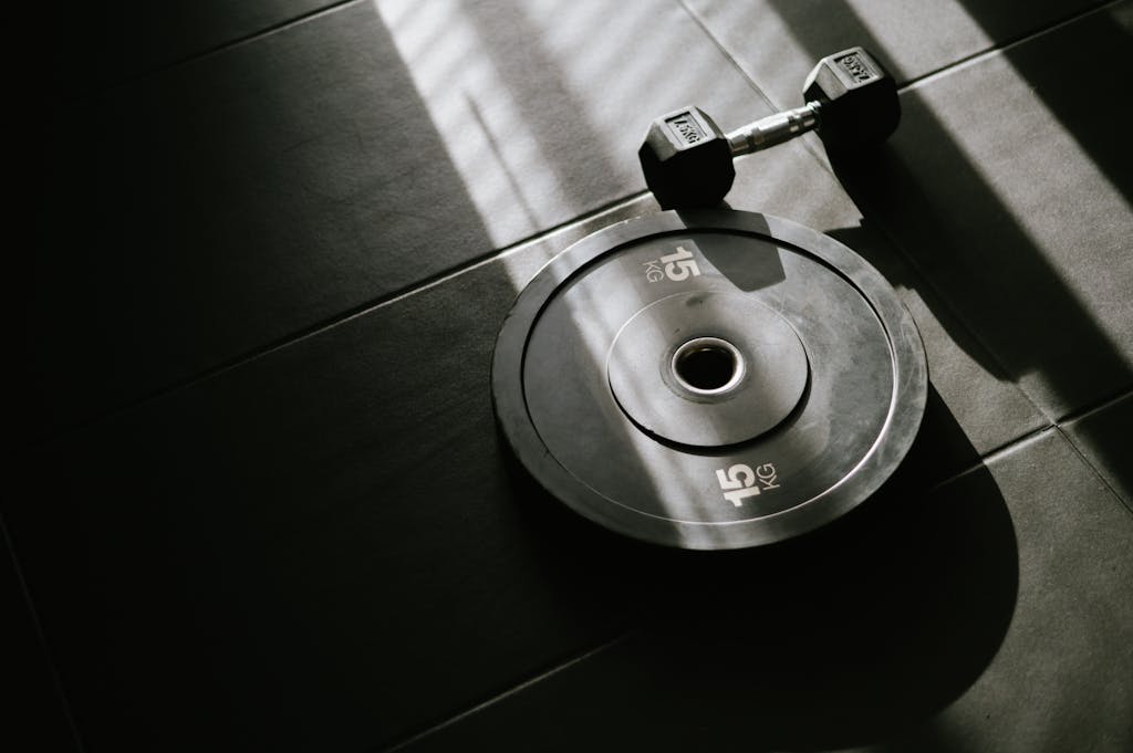 A black and white photo of a dumbbell on a tiled floor