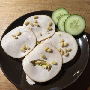 Volkoren crackers met avocado, kipfilet en pijnboompitten