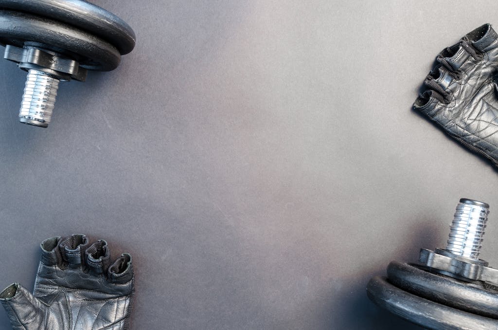 Flat lay of dumbbells and gloves on a workout surface, ready for training.