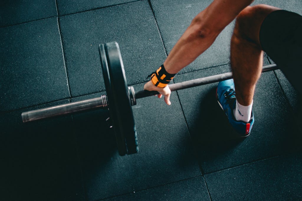 Close up van een persoon die een barbell optilt in een indoor gym